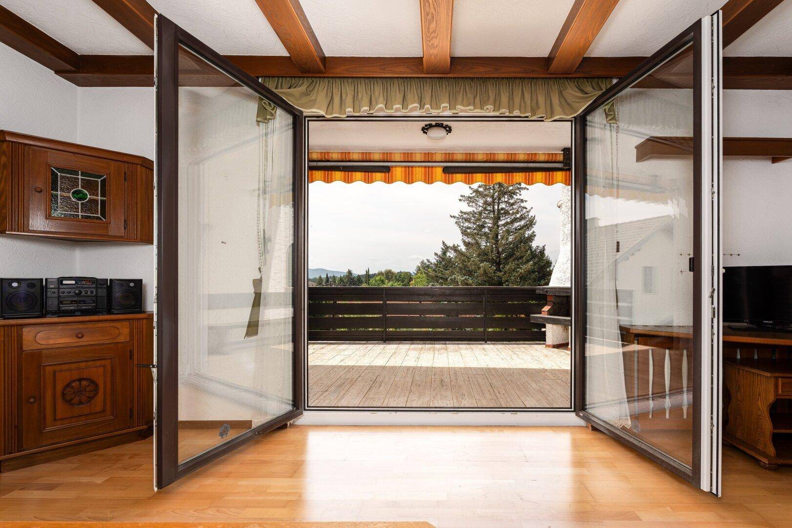 Offener Blick vom Wohnzimmer auf den Balkon mit weitreichender grüner Aussicht.