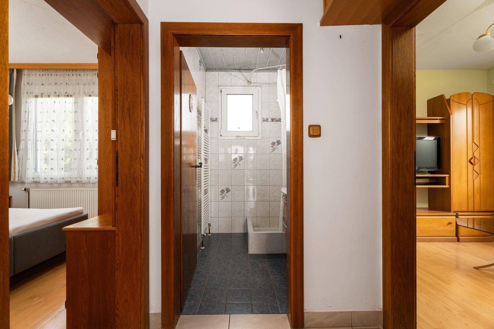 Blick durch eine Tür in ein Badezimmer mit Fliesen und Fenster.