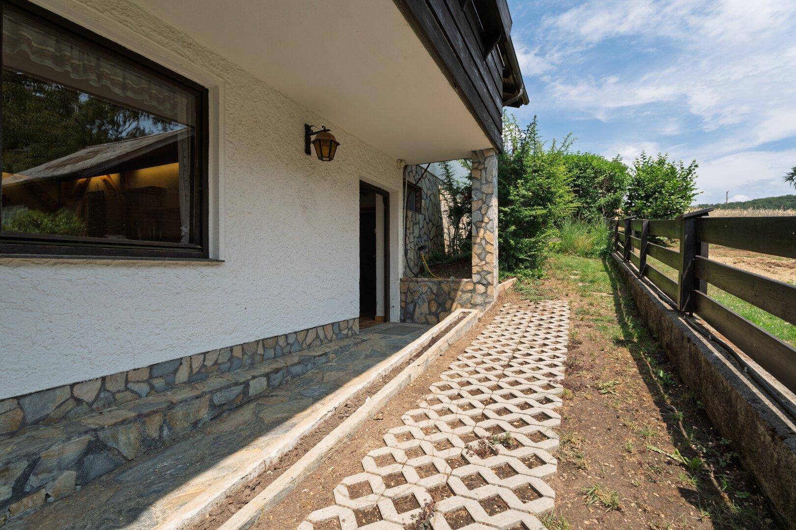 Seitenansicht des Hauses mit einem gepflasterten Weg und angrenzendem Gartenbereich.