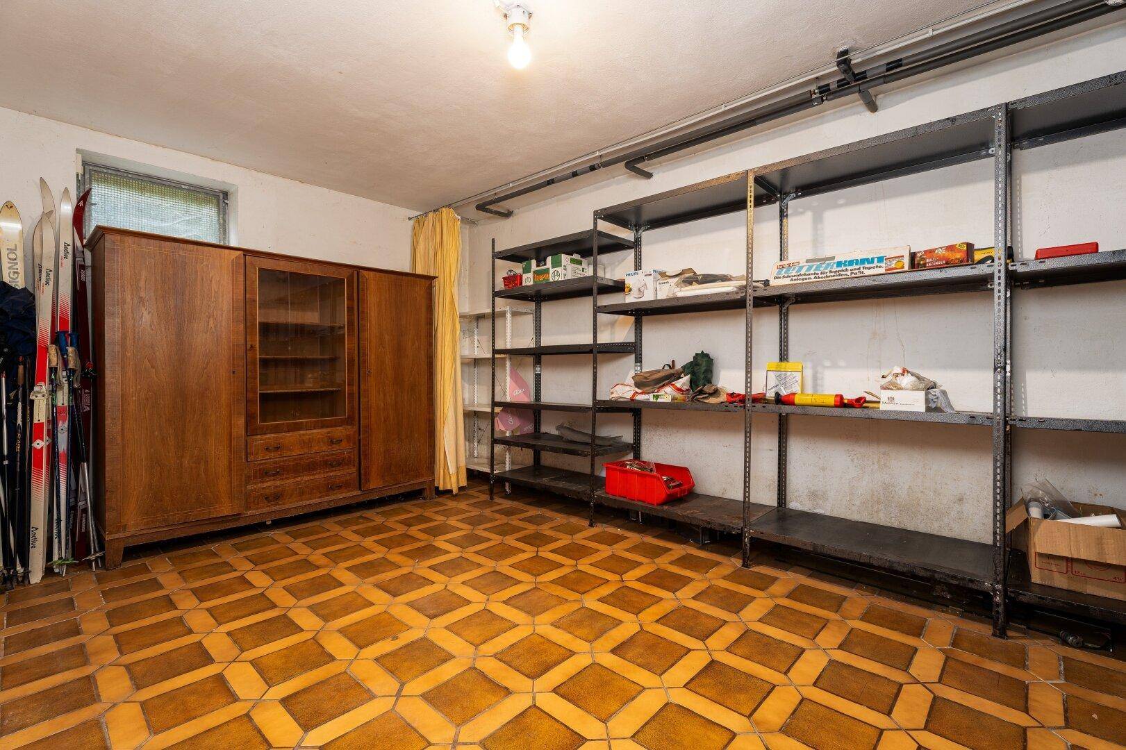 Geräumiger Kellerraum mit praktischen Regalen, Holzschrank und Fliesenboden, ideal als Abstellfläche.