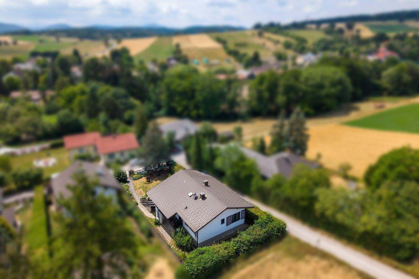 Luftaufnahme eines Einfamilienhauses in ländlicher Umgebung mit grünen Feldern und Bäumen.