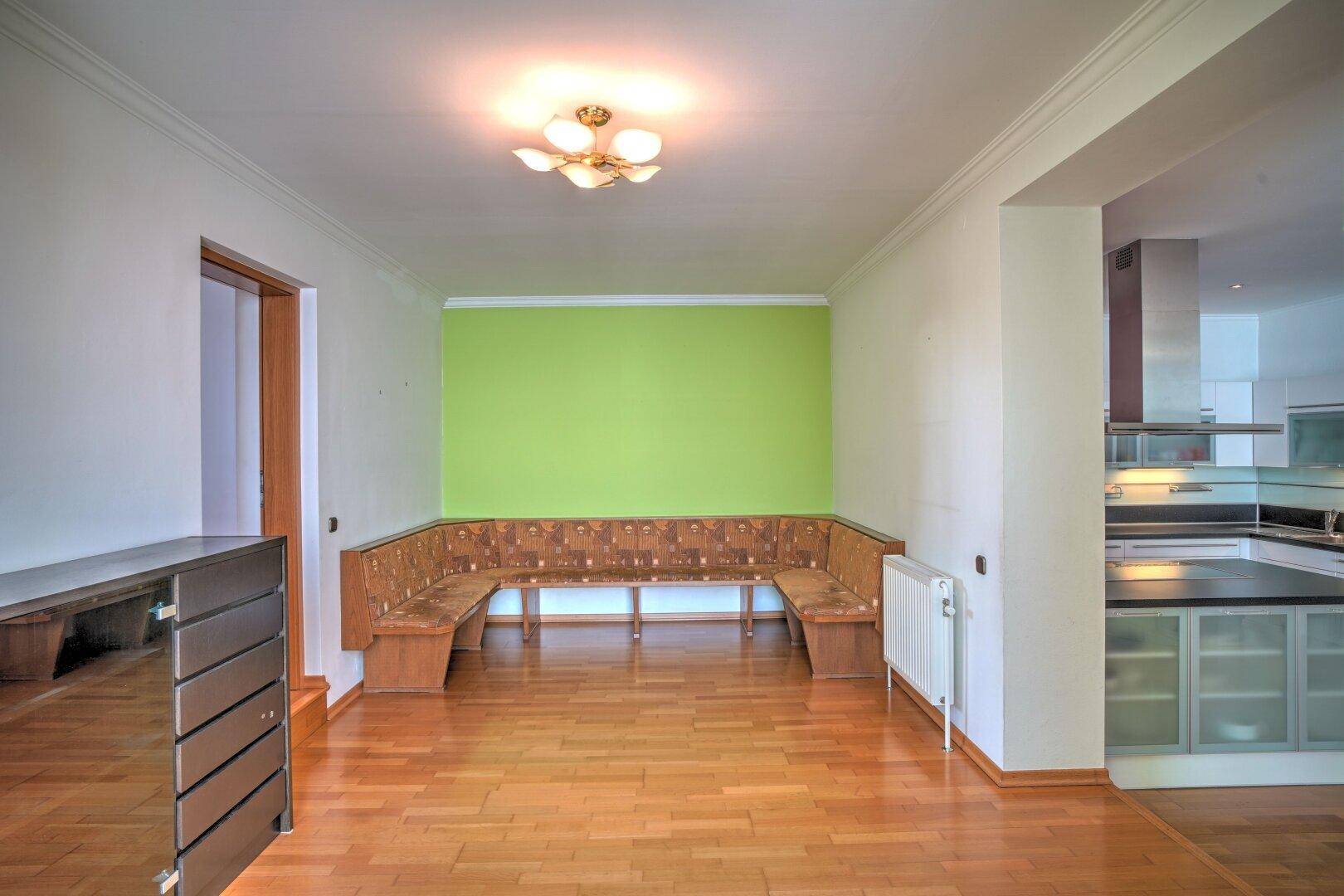 Gemütlicher Essbereich mit Holzboden, eingebauter Sitzbank und farbiger Akzentwand.