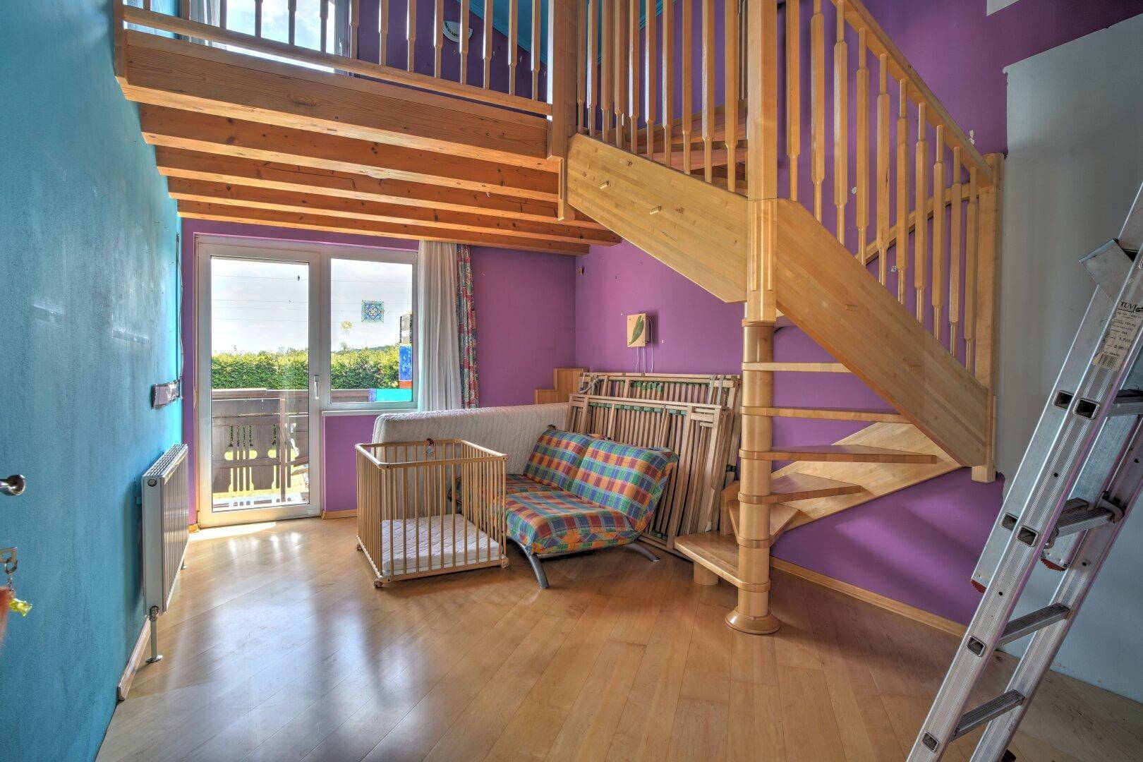 Kinderzimmer mit Holztreppe zu einem Hochbett, Balkonzugang und farbigen Wänden.