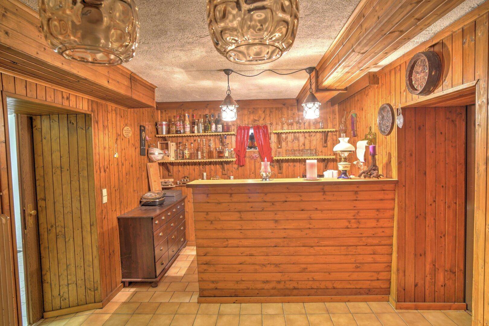 Gemütlicher Partykeller mit Holzvertäfelung, Bar und rustikaler Einrichtung.