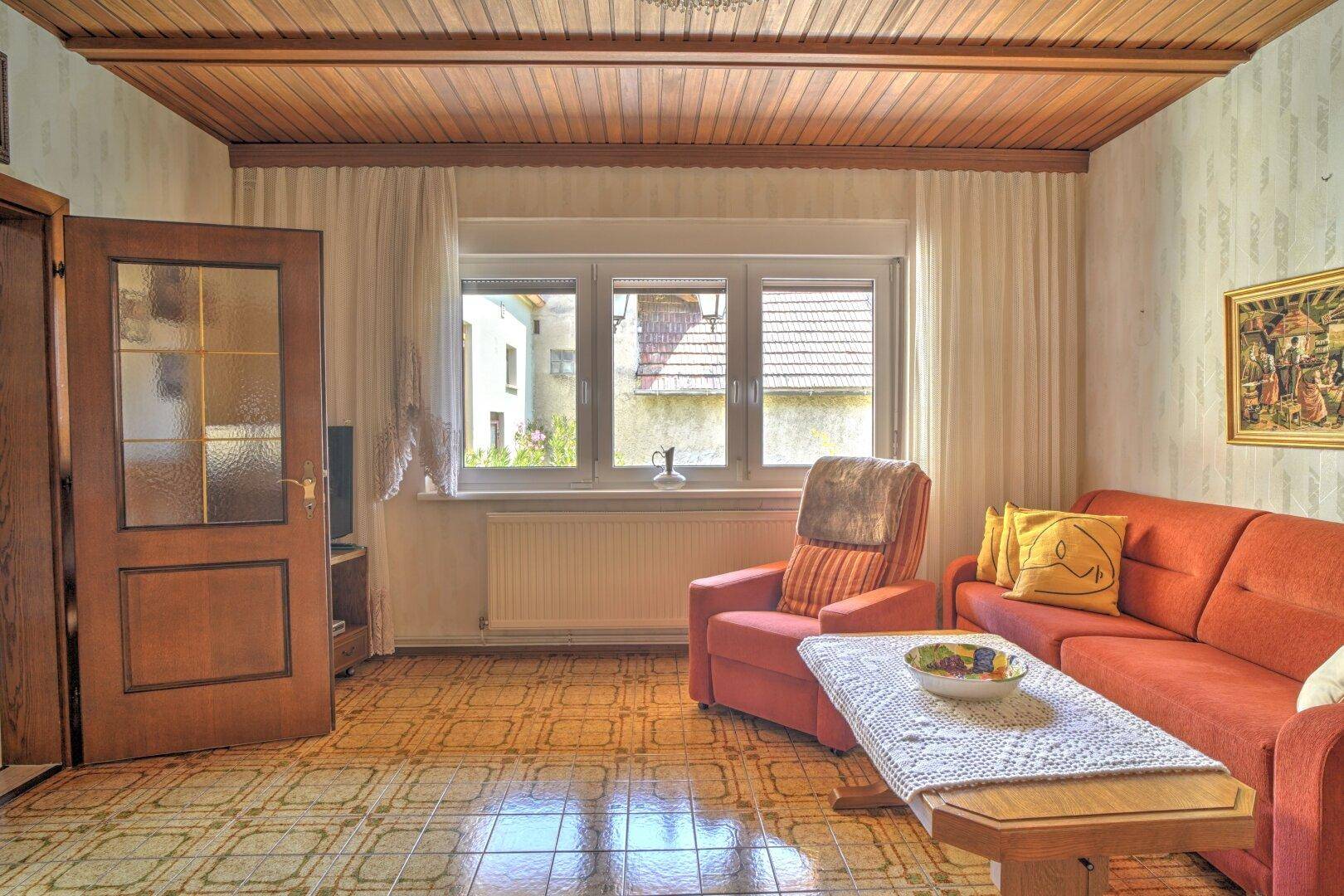 Wohnzimmer mit traditionellen Möbeln, Kachelofen und Fensterblick, bietet eine warme Atmosphäre.