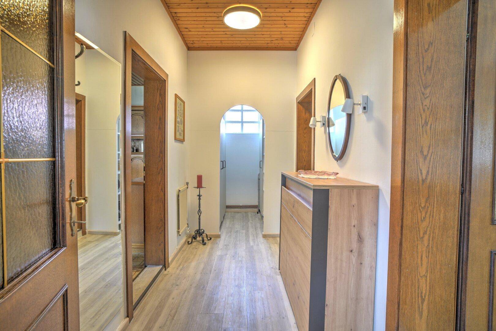 Heller Flur mit Holzdecke und modernem Schuhschrank, führt zu weiteren Räumen.