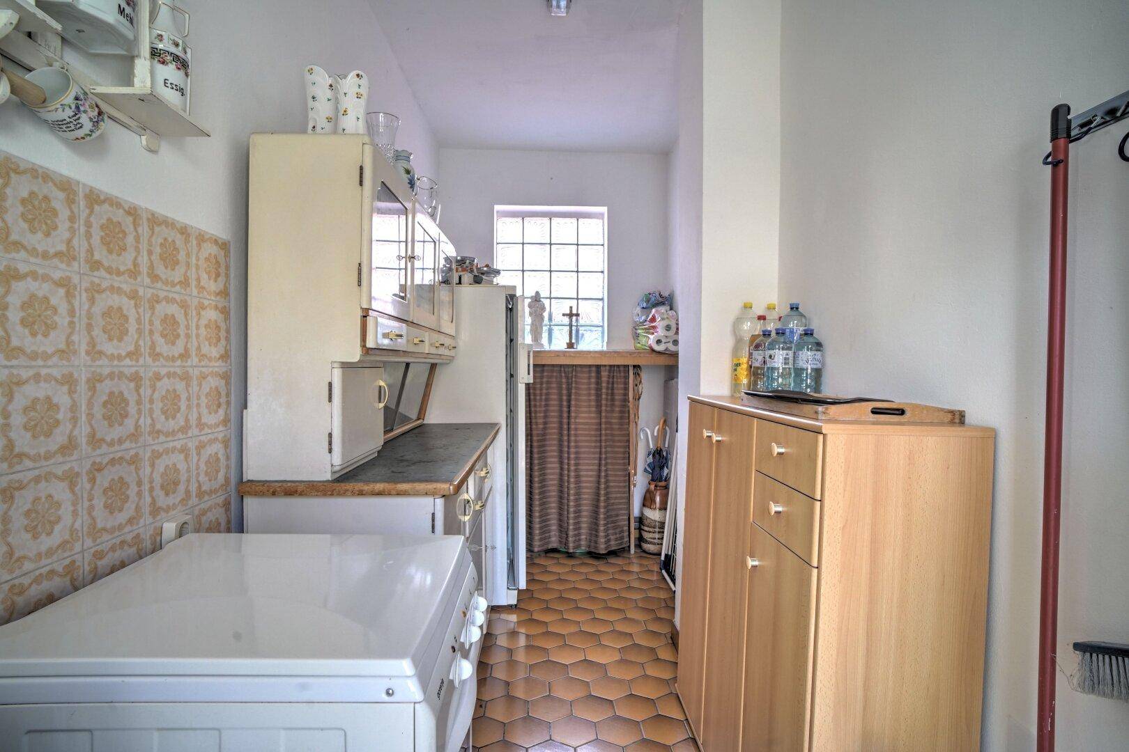 Einfache Waschküche mit Spülbecken, Regalen und Fenster, funktional eingerichtet.