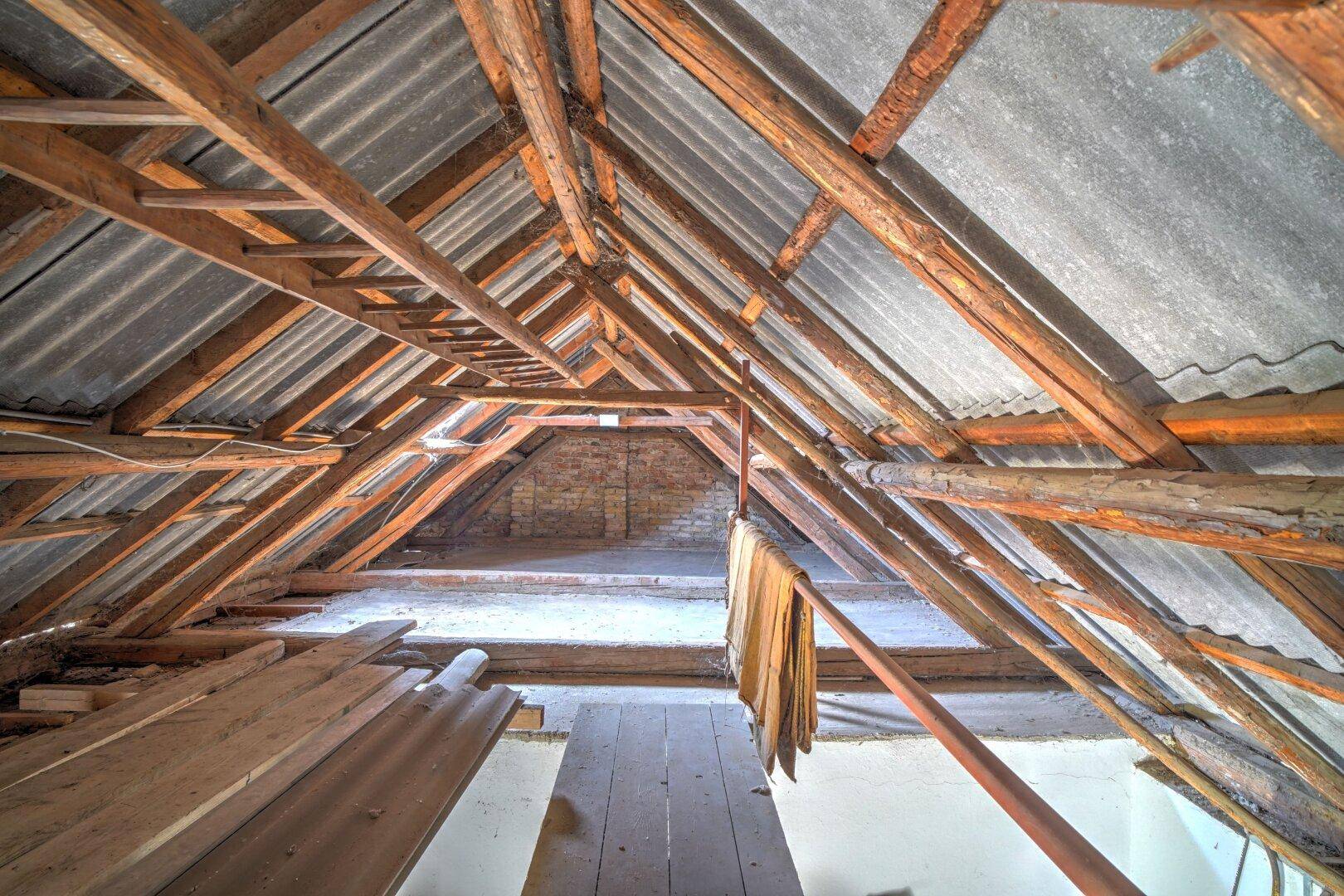 Geräumiger Dachboden mit freiliegenden Holzbalken und Wellblechdach, ideal als Lagerfläche.