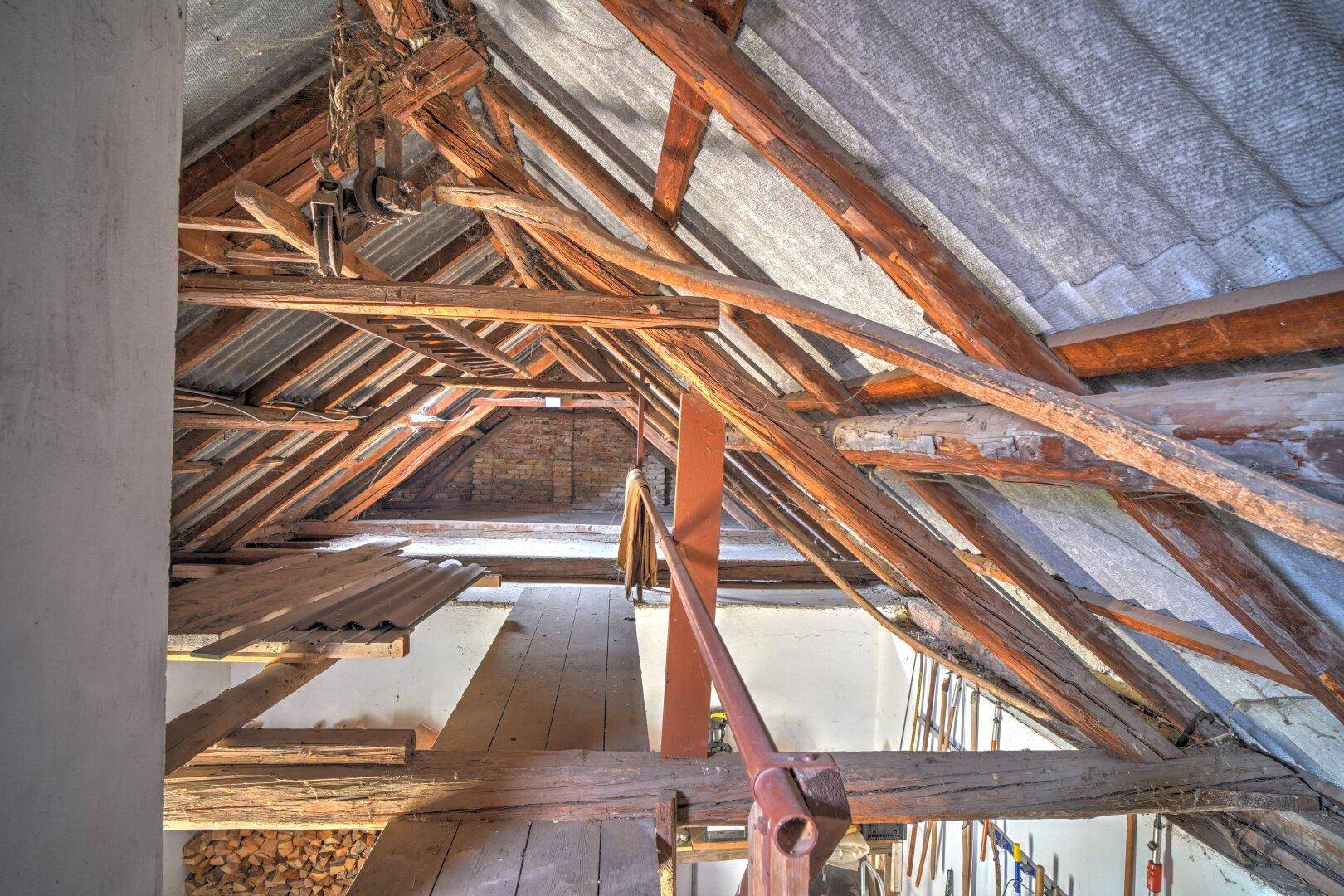 Dachbodenbereich mit robuster Holzkonstruktion und Blick auf die Ziegelwände, viel Stauraum.
