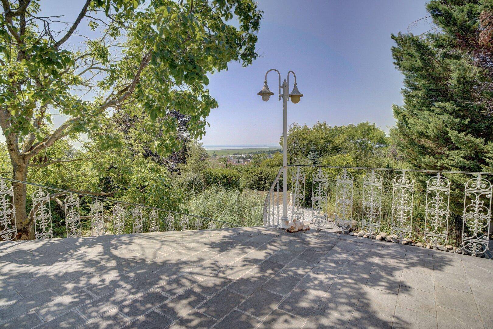 Obere Terrasse mit schmiedeeisernem Geländer und weitem Blick über die Landschaft.