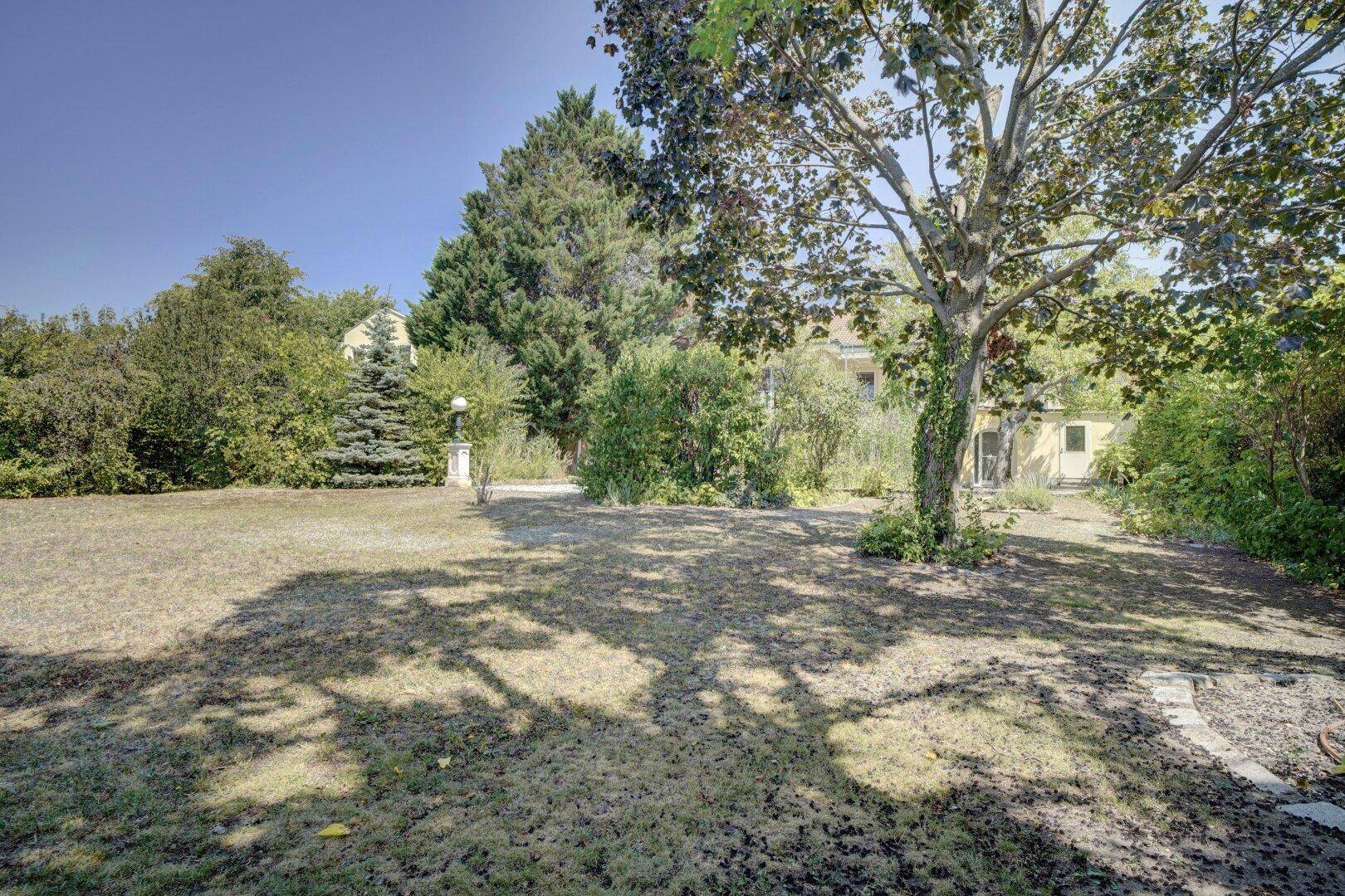 Weitläufiger Garten mit Rasenfläche, Bäumen und Blick auf das Anwesen.