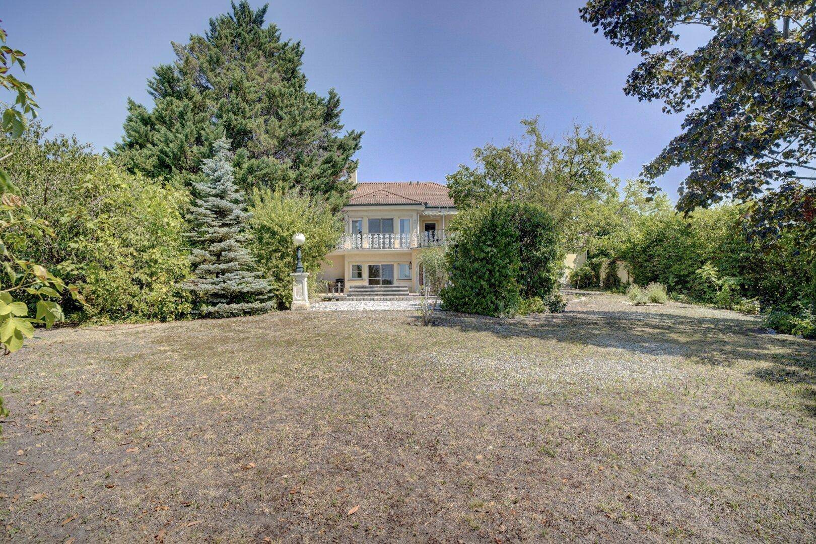 Großzügiger Garten mit Rasenfläche und Blick auf die Villa im Hintergrund.