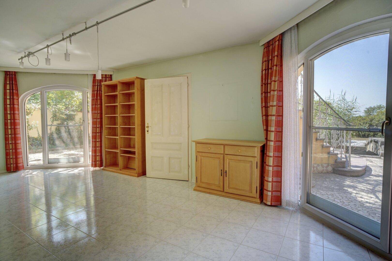 Helles Wohnzimmer mit großen Rundbogenfenstern und direktem Zugang zur Terrasse.