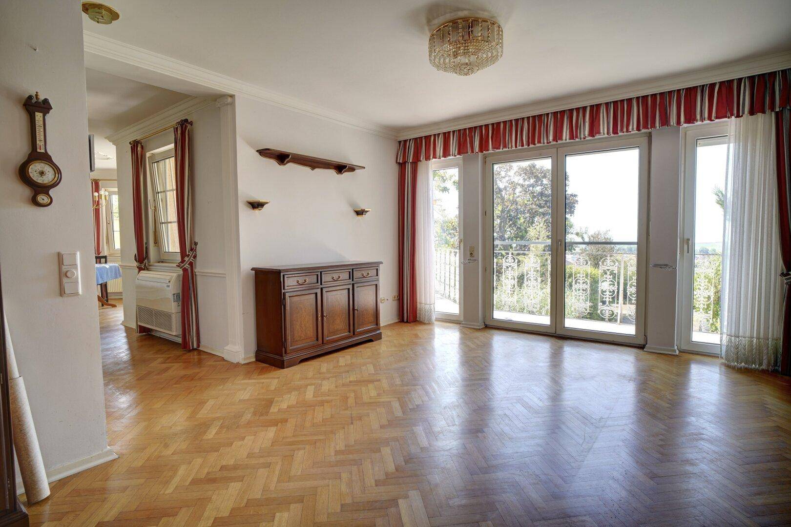 Helles Wohnzimmer mit Parkettboden, großen Fenstern und Blick ins Grüne.