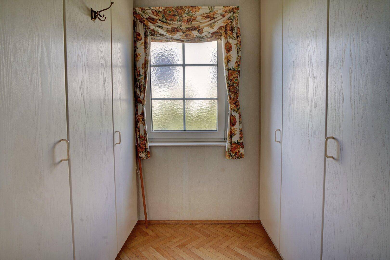 Kleiner Raum mit Fenster und Einbauschränken, ideal als Ankleidezimmer oder Abstellraum.