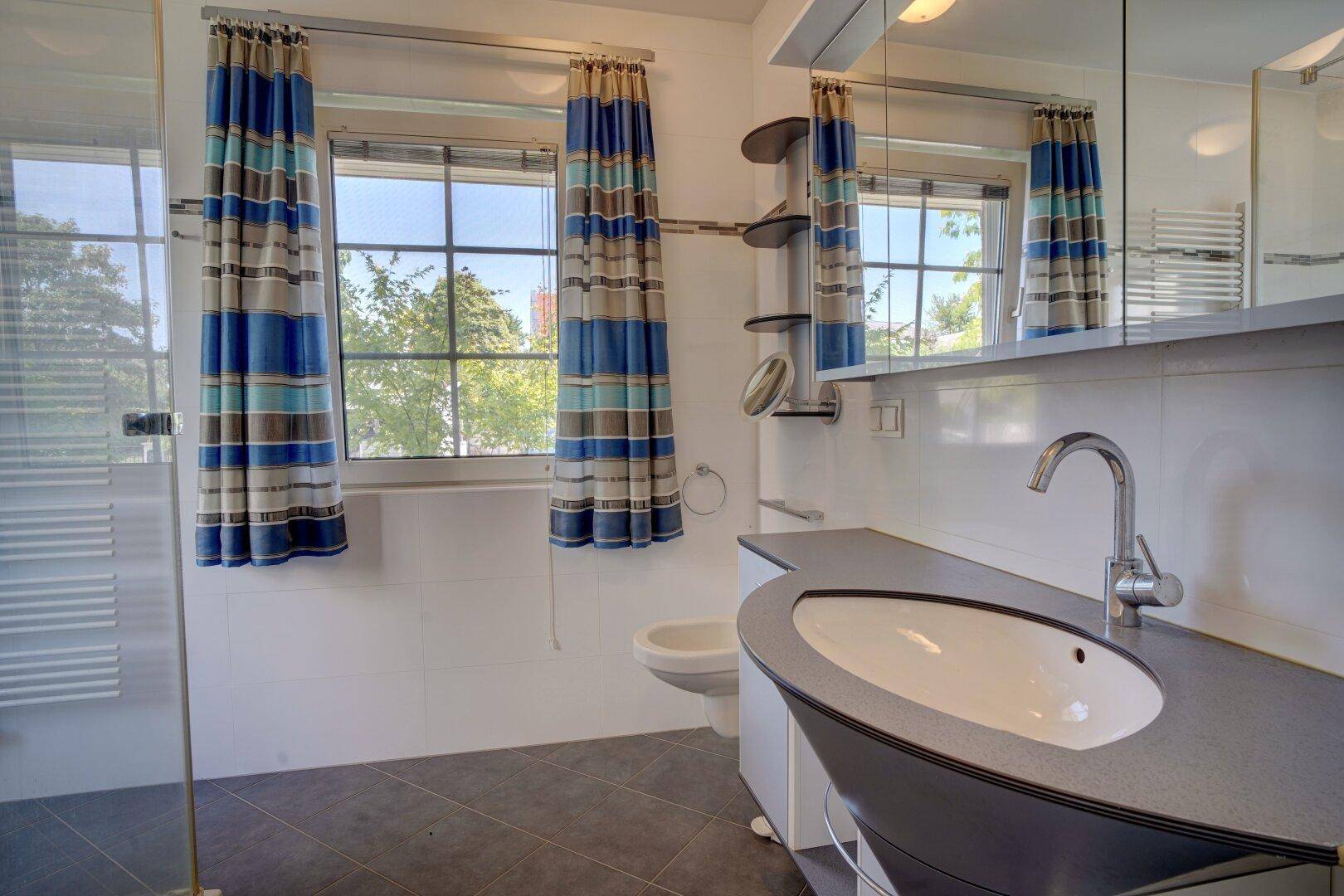 Modernes Badezimmer mit stilvollem Waschbecken, Dusche und Fenster.