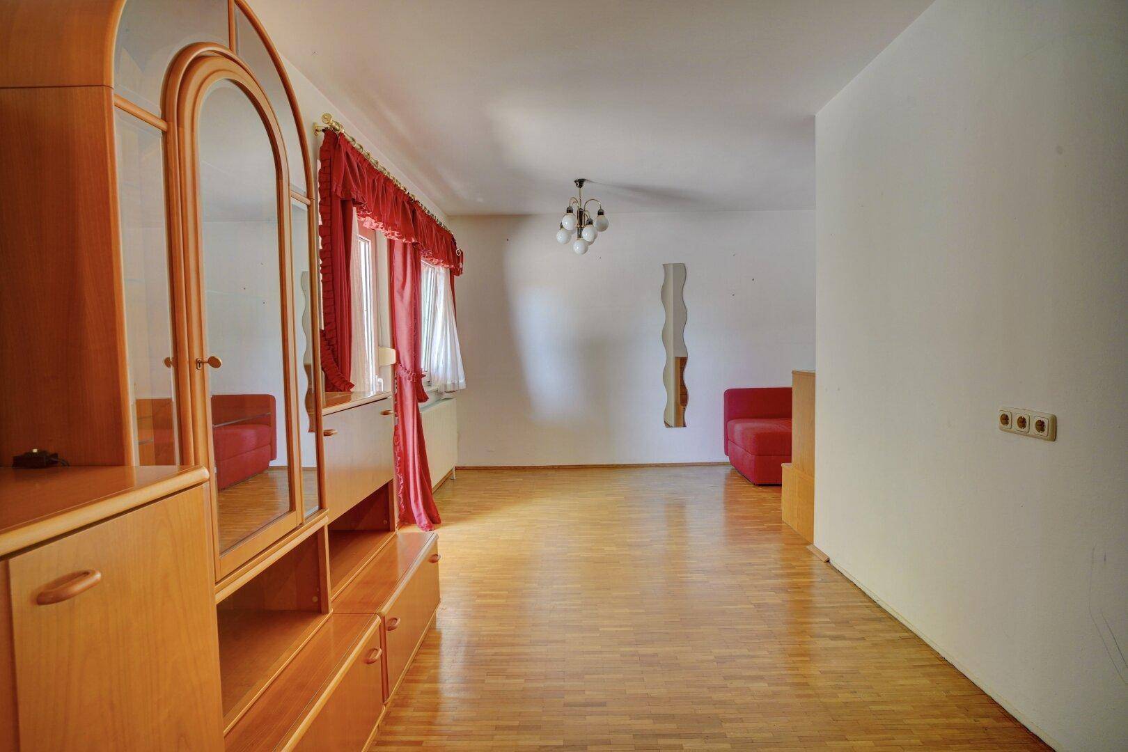 Helles Zimmer mit Parkettboden und Schrankwand, vielseitig nutzbar.