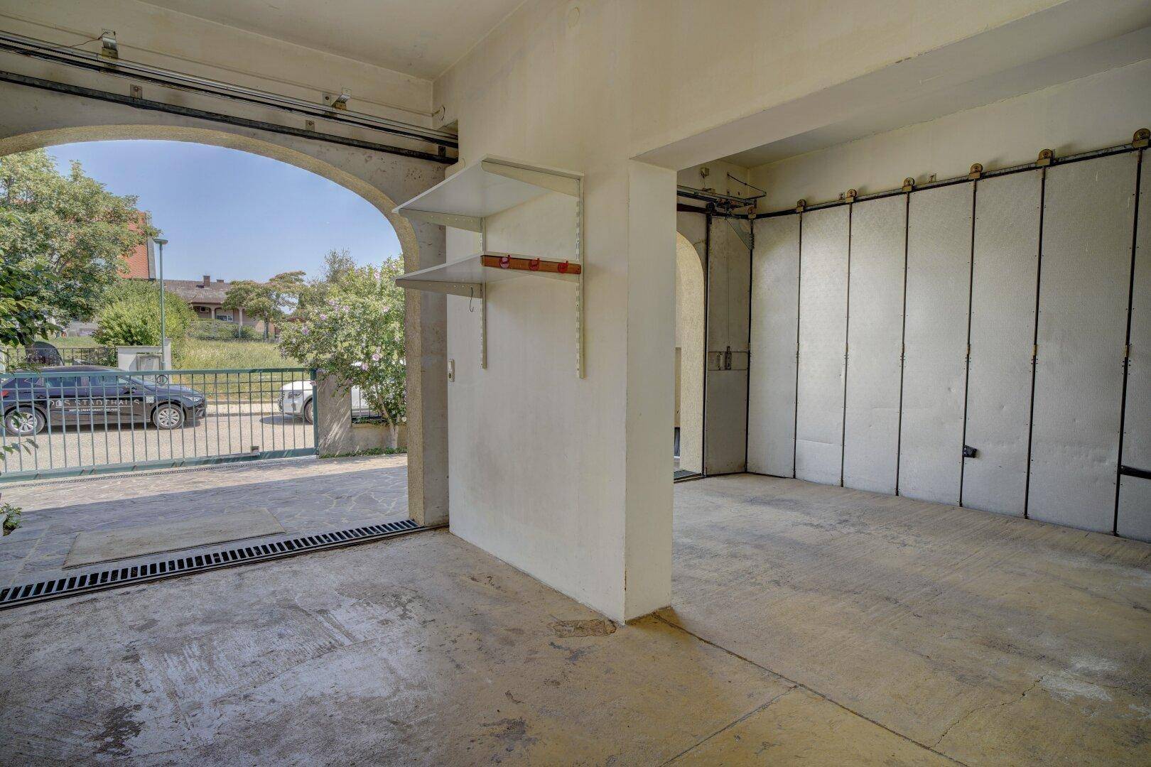 Geräumige Garage mit Betonboden und offenem Zugang zur Einfahrt des Grundstücks.