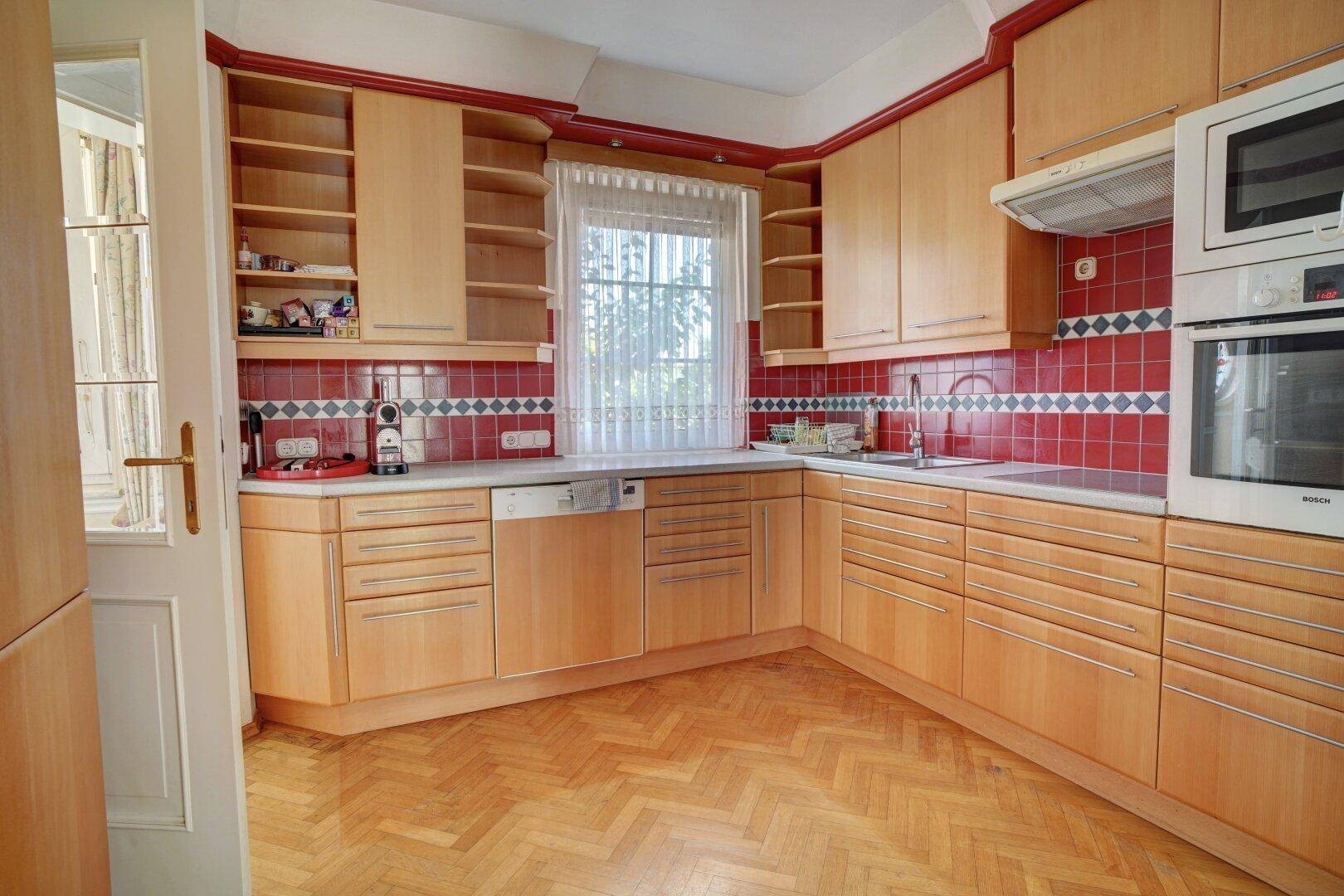 Traditionelle Küche mit Holzschränken, roten Fliesen und integrierten Geräten.