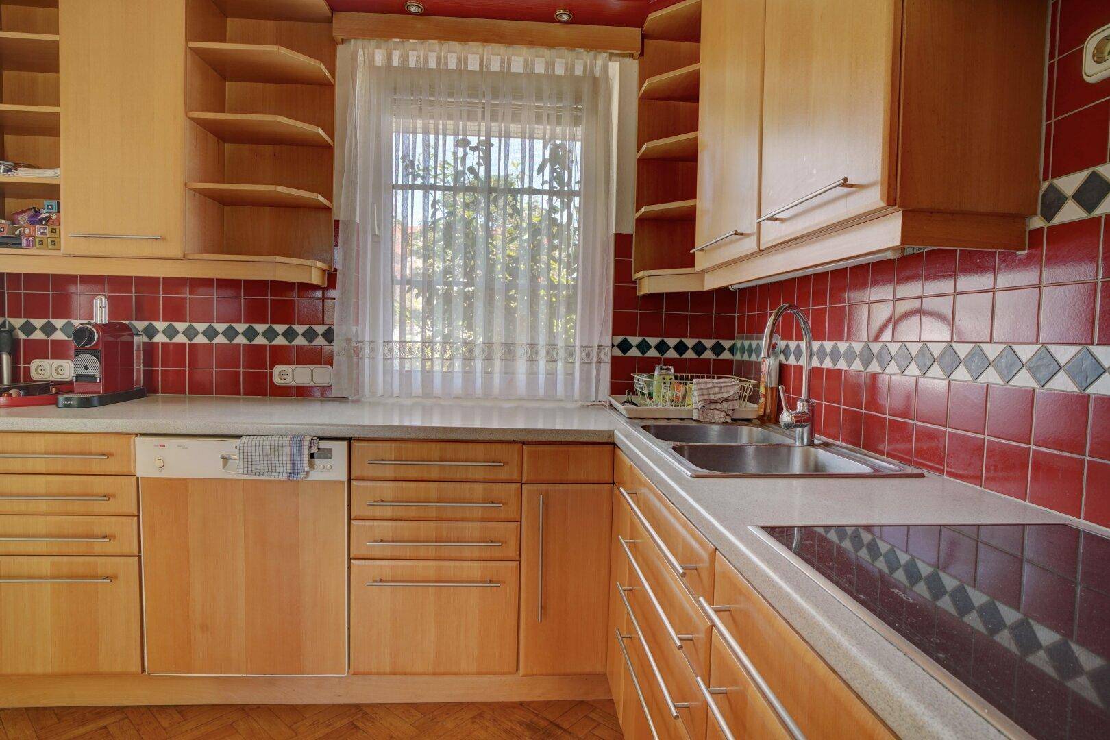 Funktionale Küche mit Holzfronten, rotem Fliesenspiegel und Induktionskochfeld.