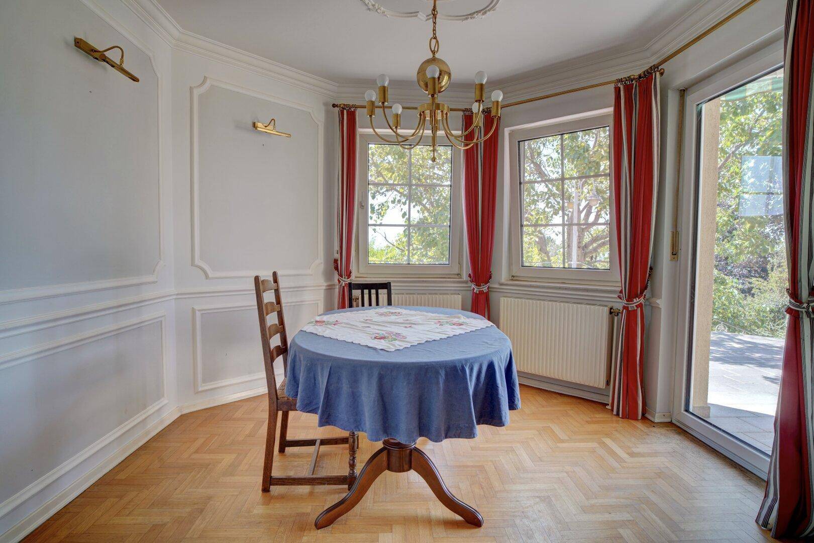 Gemütlicher Essbereich mit Parkettboden, klassischem Esstisch und großen Fenstern.