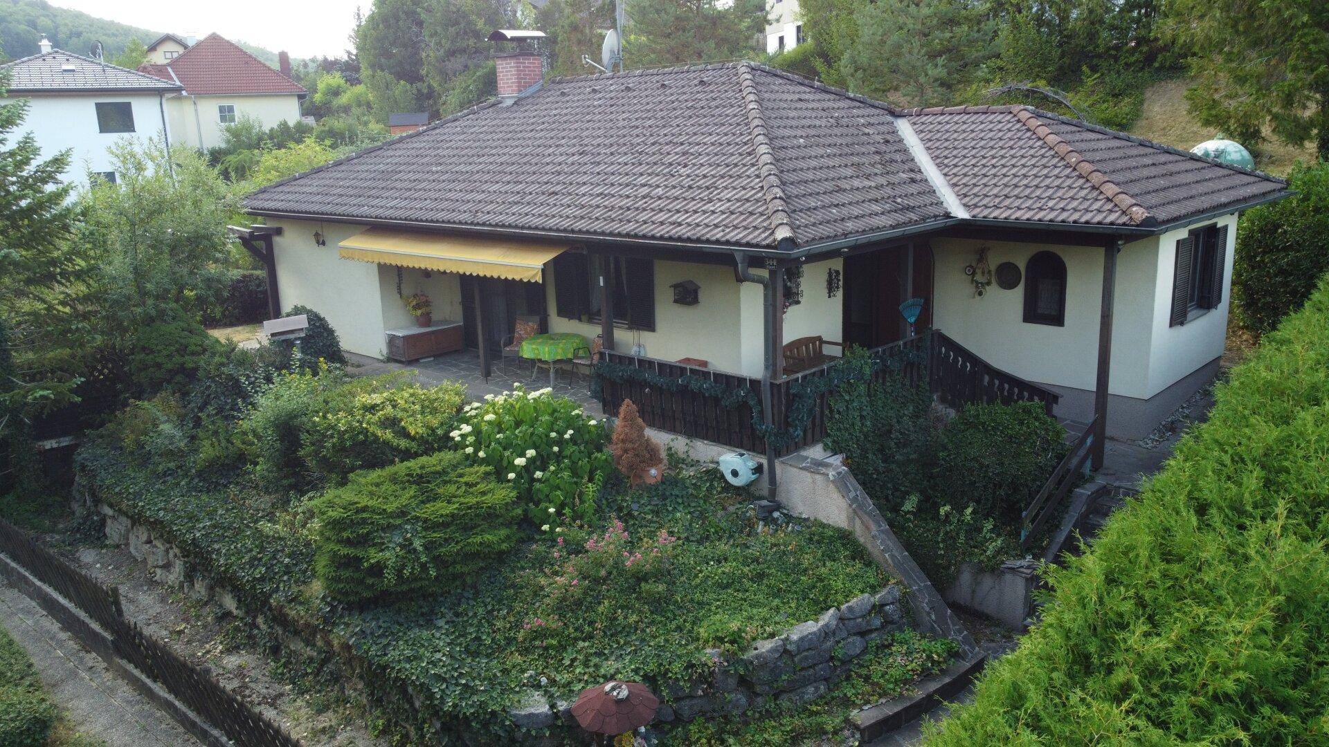 Charmantes Einfamilienhaus mit gepflegtem Garten und überdachtem Eingangsbereich in grüner Umgebung.