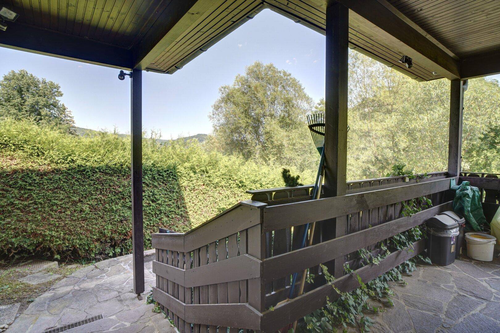 Überdachte Terrasse mit Holzbalken und weitem Blick in die grüne Landschaft.