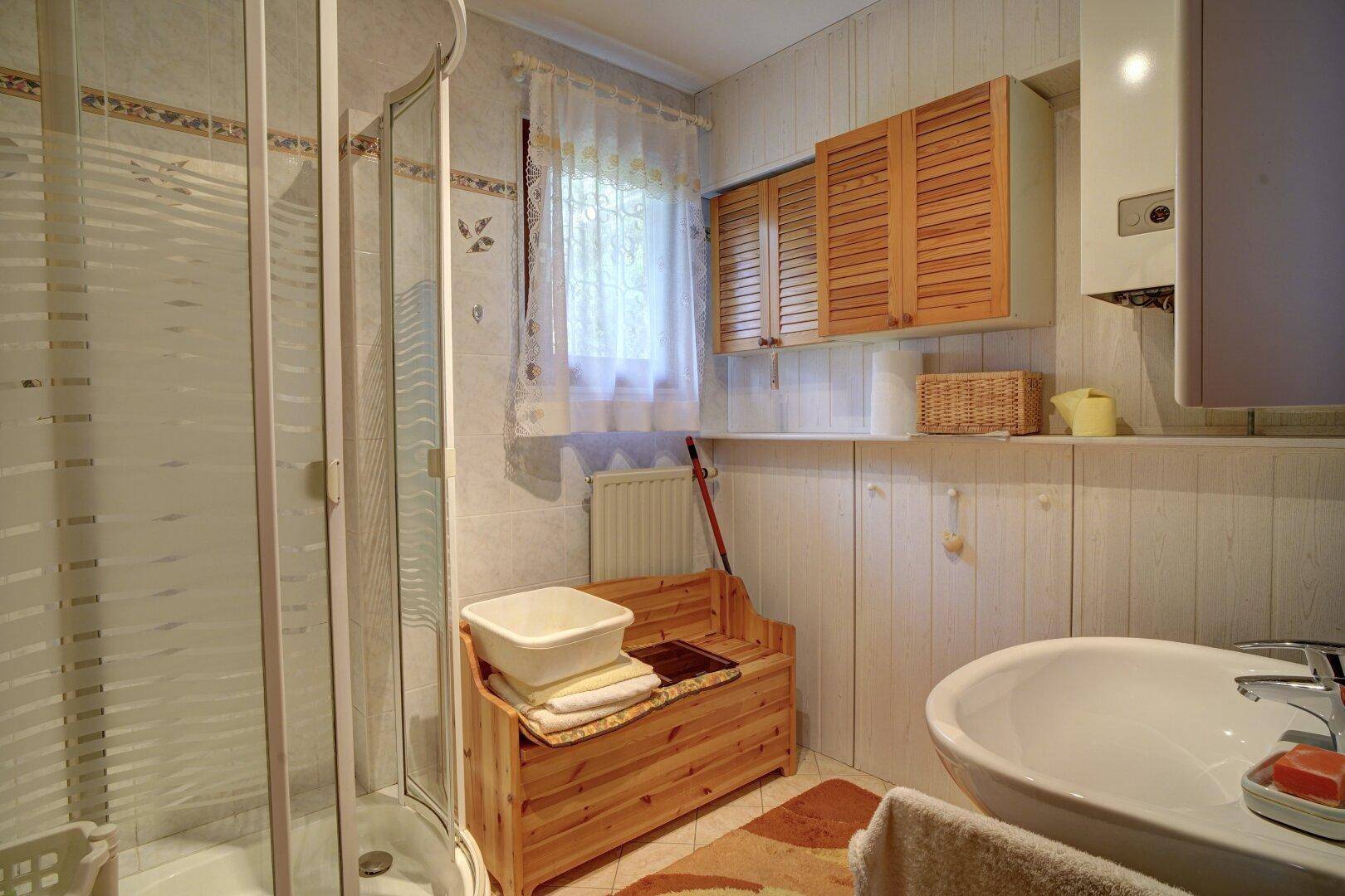 Badezimmer mit Duschkabine, Waschbecken und Fenster für Tageslicht.