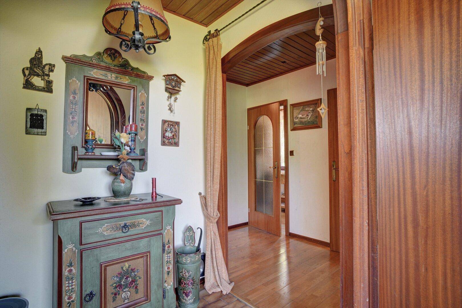 Gemütlicher Flur mit traditionellen Holzmöbeln, Spiegel und Holzbalkendecke.