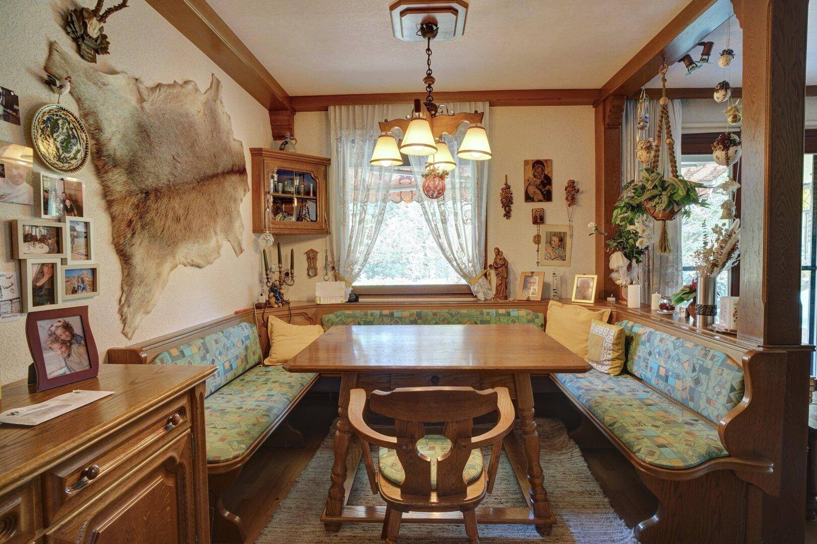 Rustikaler Essbereich mit Holztisch, Eckbank und traditioneller Dekoration.