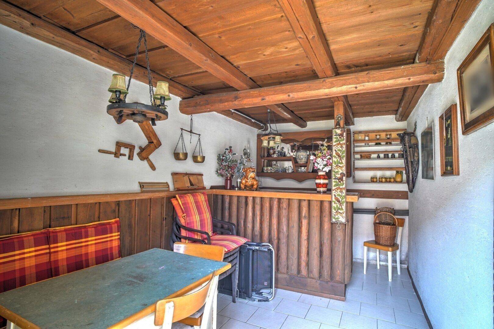 Rustikaler Raum mit Holzvertäfelung, Bar und Sitzgelegenheiten, ideal für gesellige Abende.