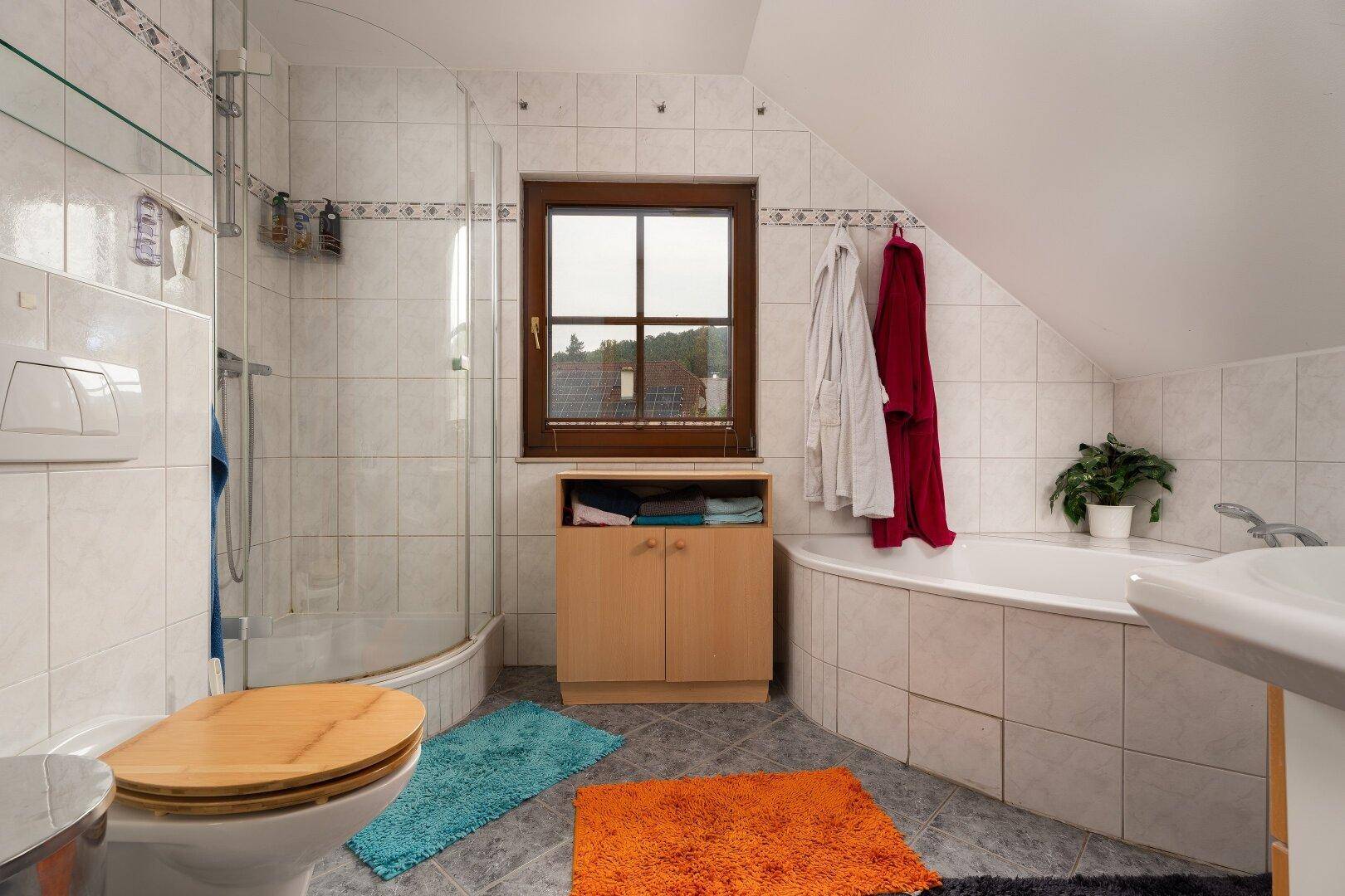 Badezimmer im Dachgeschoss mit Dusche, WC, Eckbadewanne und Fenster.