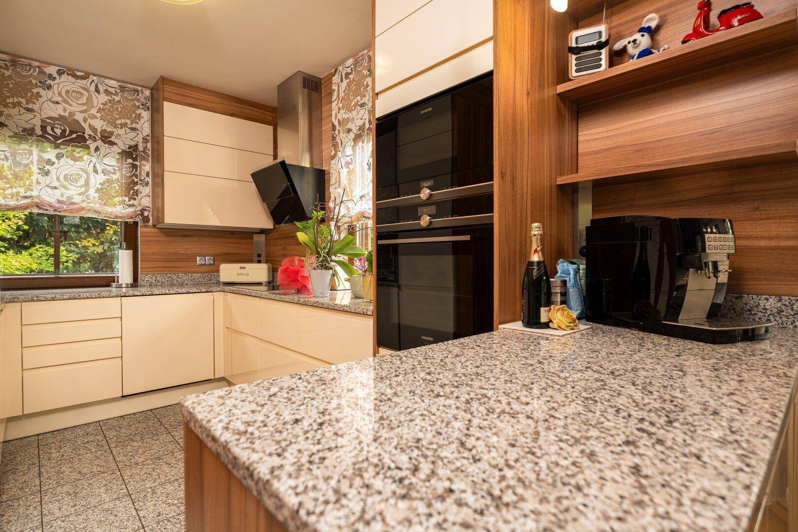 Moderne Einbauküche mit Granitarbeitsplatten, integrierten Geräten und Holzdetails.