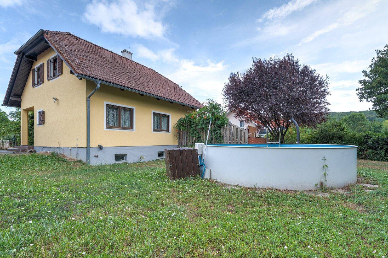 Seitenansicht des Hauses vom Garten aus mit Rasenfläche und einem Aufstellpool.