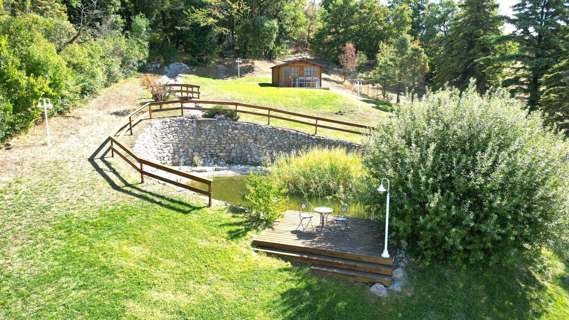 Idyllischer Gartenbereich mit Teich, Holzsteg und kleinem Gartenhaus, ideal zum Entspannen.