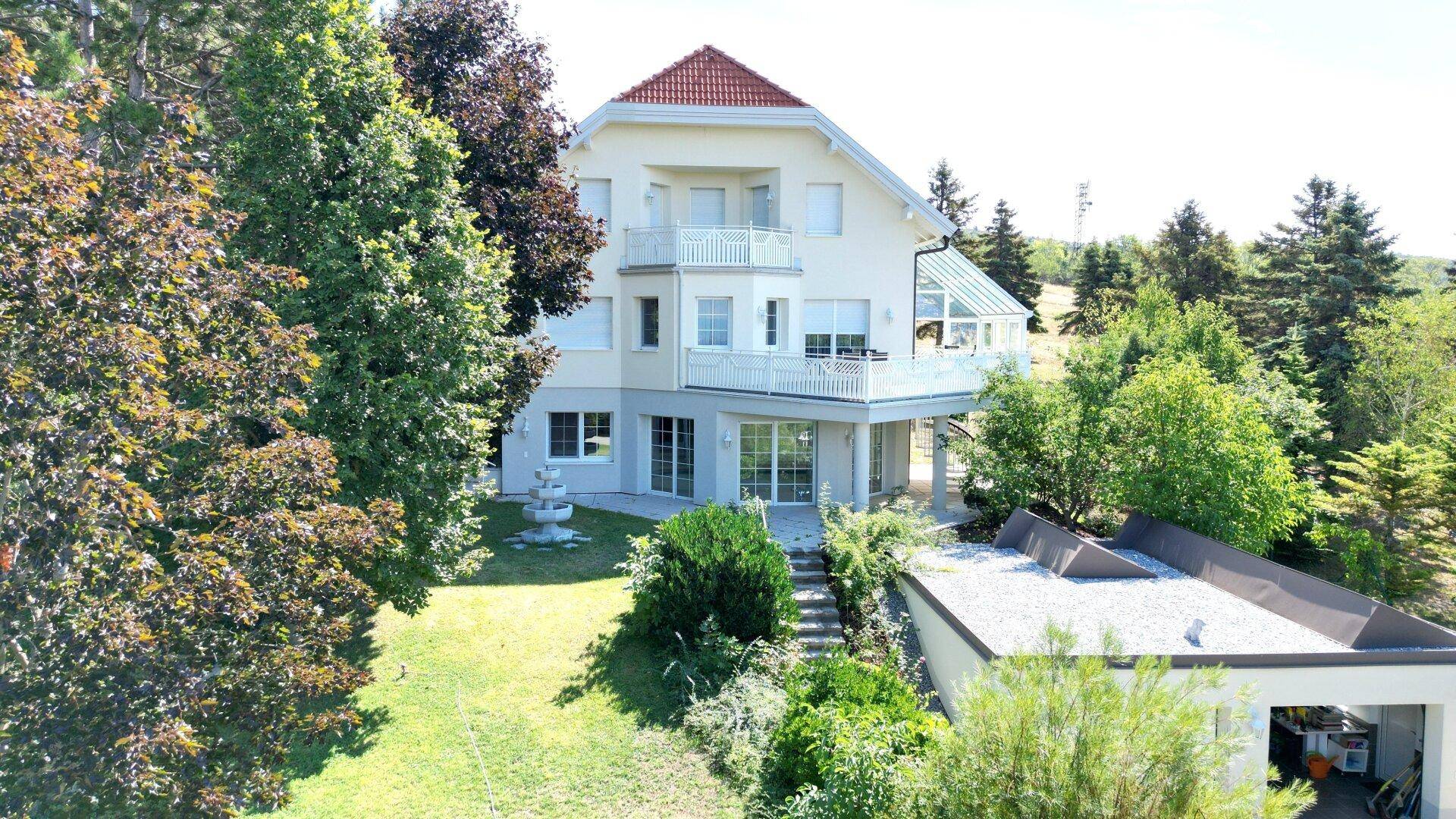 Großzügiges Haus mit mehreren Balkonen, Wintergarten und weitläufigem Gartenbereich.