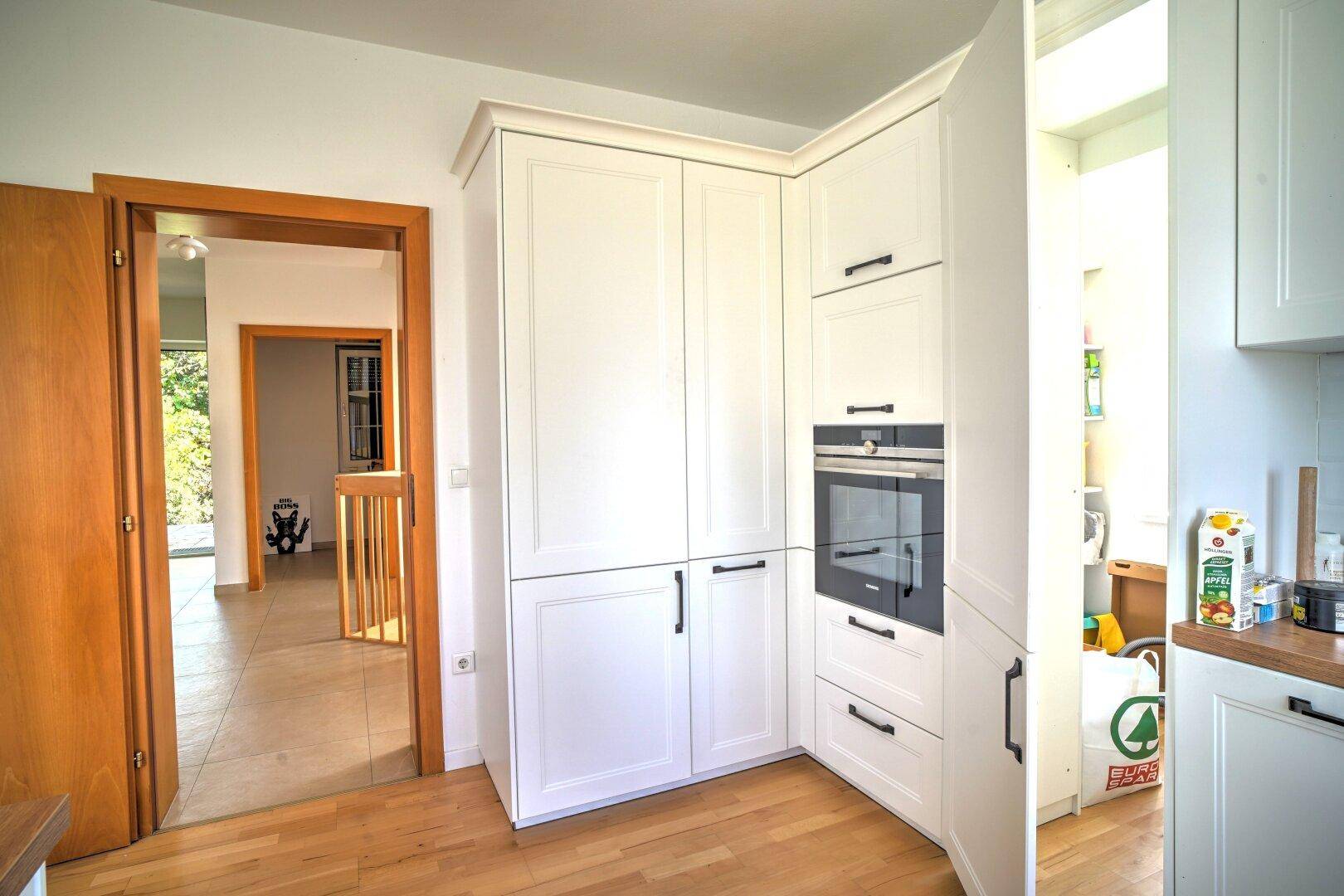 Integrierte weiße Küchenschränke mit Backofen und Zugang zum Flur und Treppenhaus.
