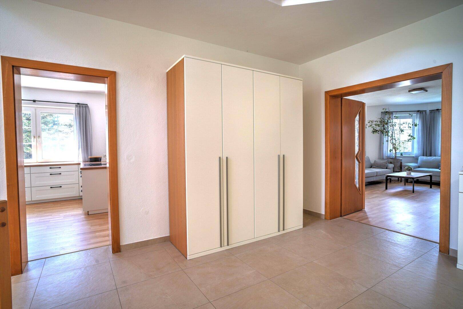 Flur mit großem Einbauschrank, Fliesenboden und Zugängen zu Küche und Wohnzimmer.