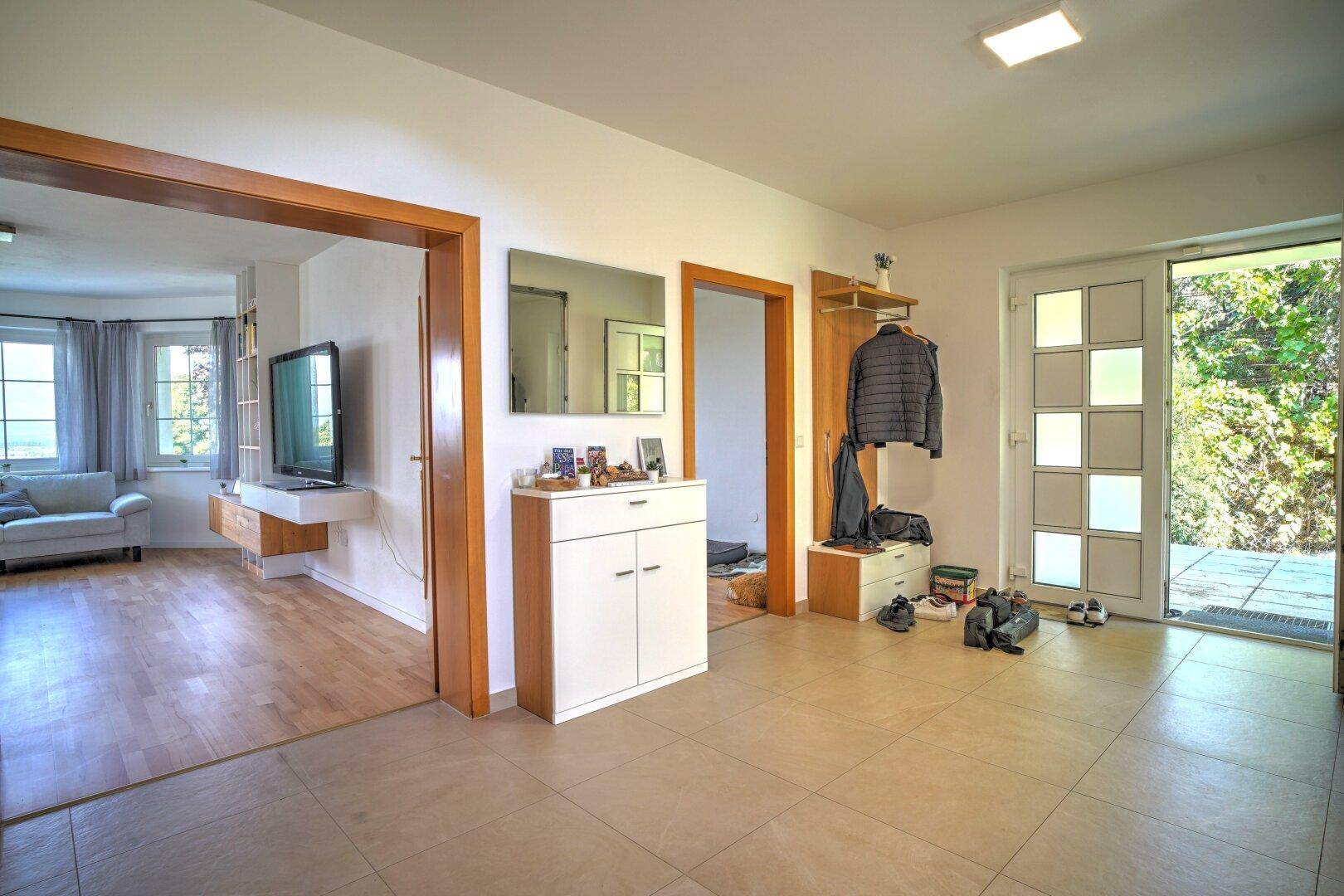 Heller Eingangsbereich mit Fliesenboden, Garderobe und direktem Zugang zur Terrasse.