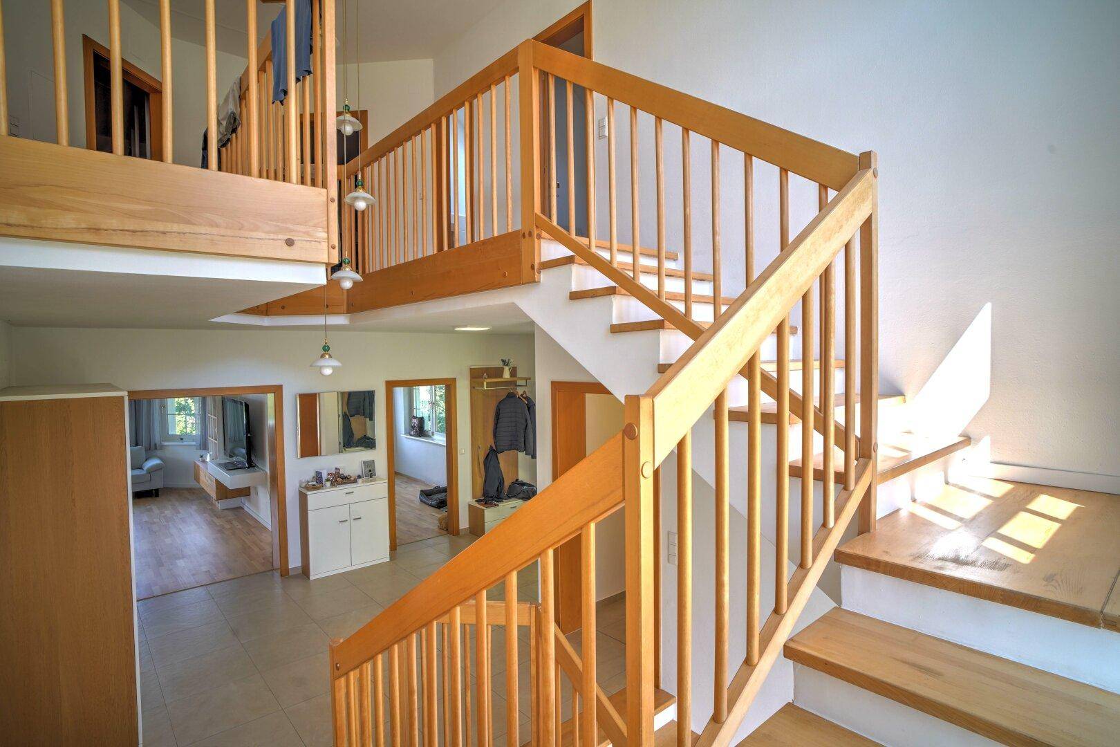 Geräumiger Flur mit heller Holztreppe, die die verschiedenen Ebenen des Hauses verbindet.
