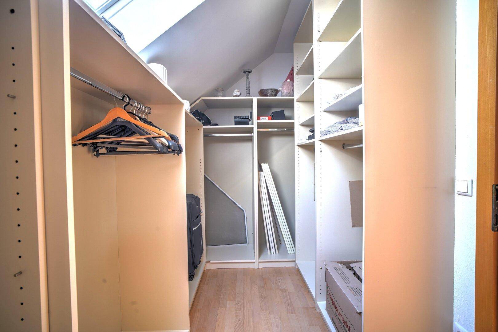 Praktischer begehbarer Kleiderschrank unter der Dachschräge mit viel Stauraum.