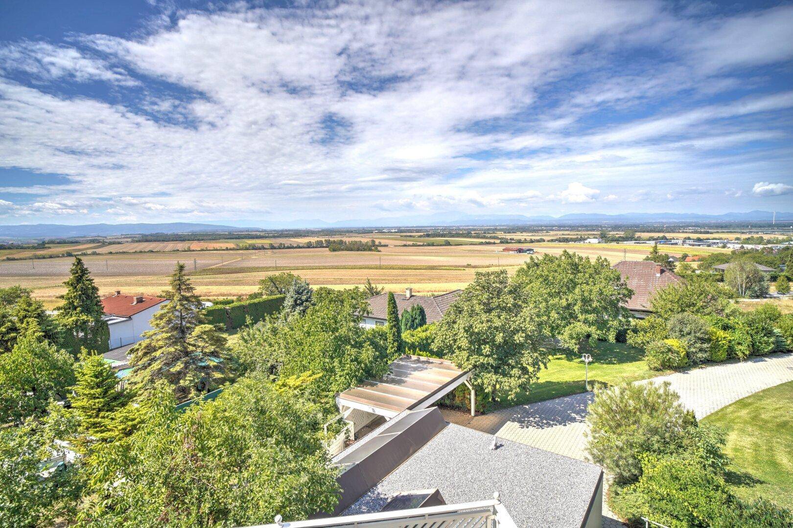 Weitläufiger Blick über Felder und grüne Landschaft unter blauem Himmel.