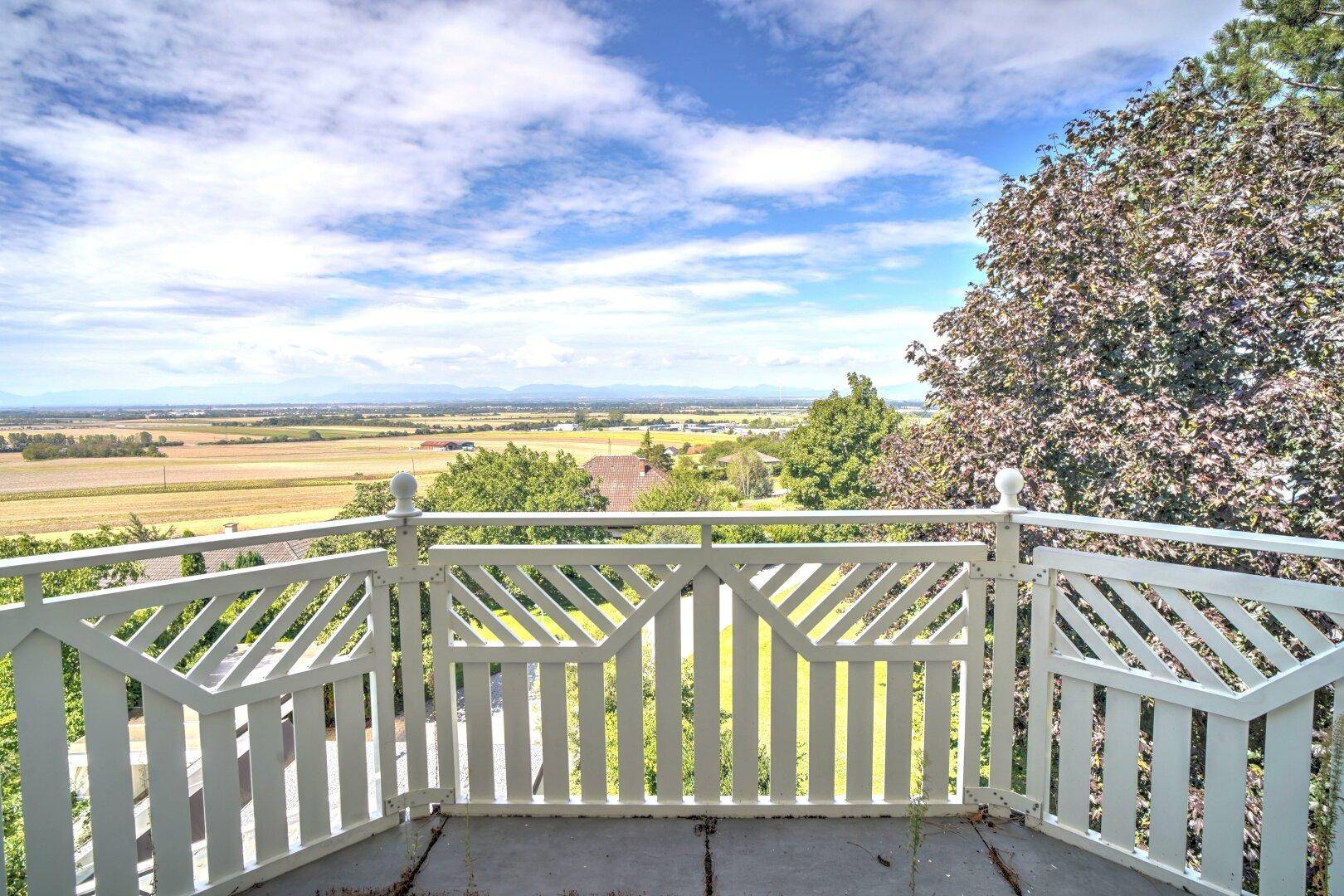 Balkon mit weißem Geländer und weitem Blick über die umliegende Landschaft.
