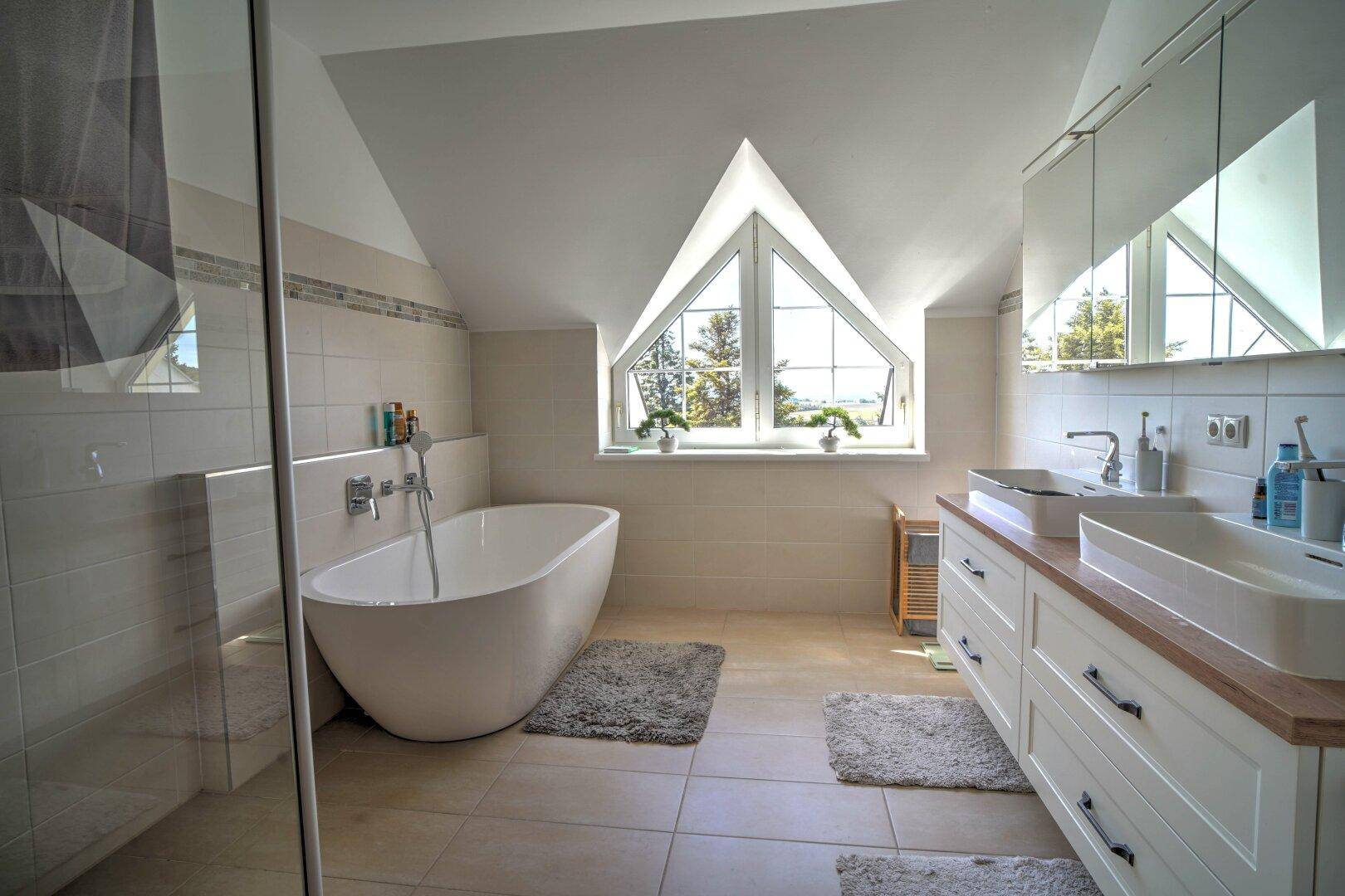 Modernes Badezimmer unter der Dachschräge mit freistehender Badewanne, Doppelwaschbecken und großem Fenster.