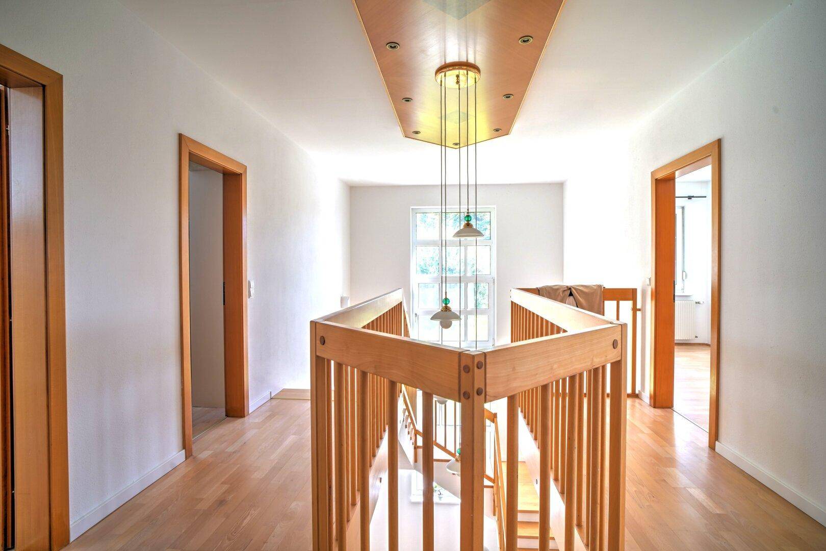Geräumiger Flur im Obergeschoss mit Holzboden und Blick auf die untere Etage.