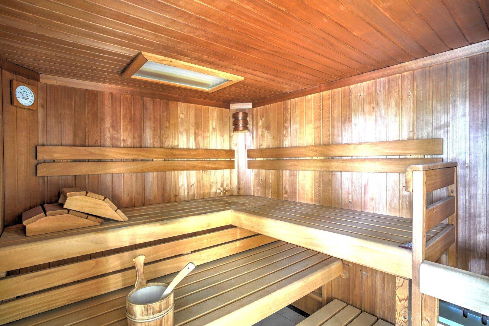 Gemütliche Holzsauna mit breiten Bänken und angenehmer Beleuchtung für Wellnessmomente.