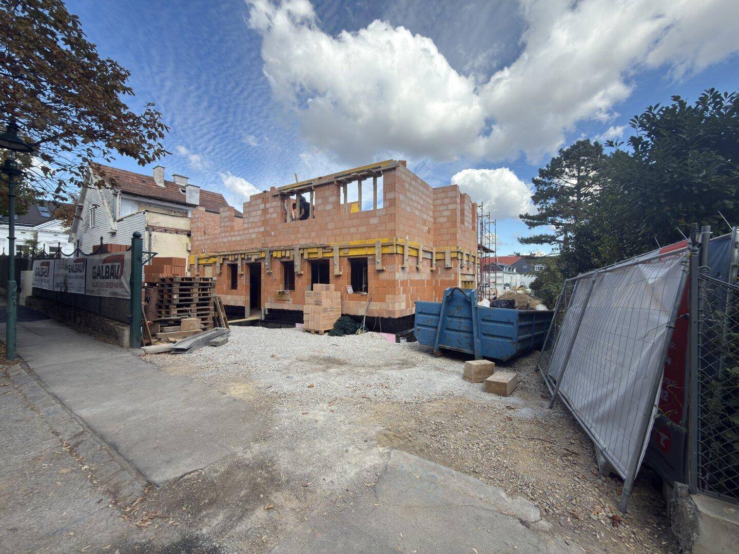 Baustelle eines Neubaus mit Rohbau und umliegender Bebauung.