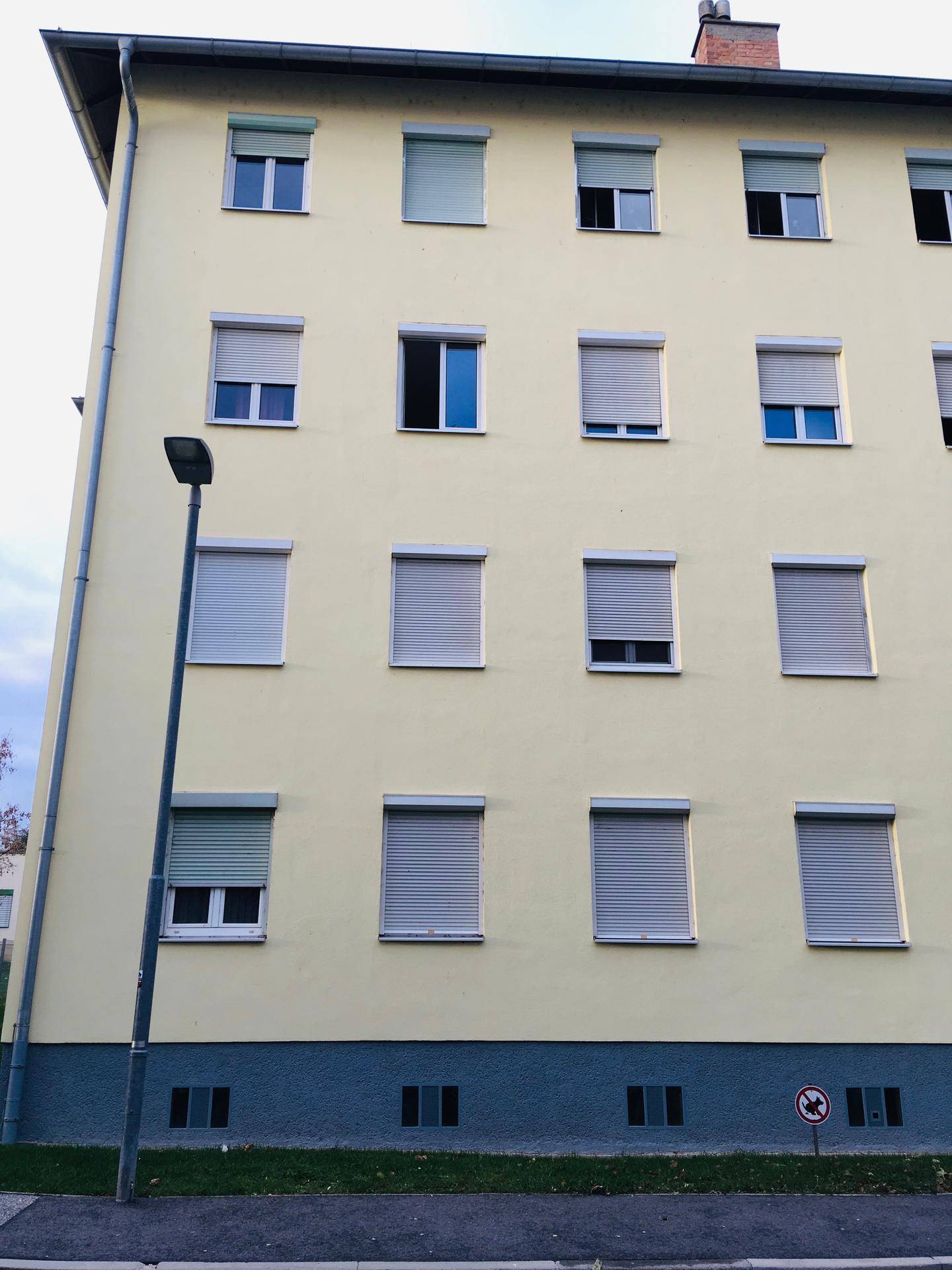 Fassade eines Mehrfamilienhauses mit zahlreichen Fenstern und Rollläden.