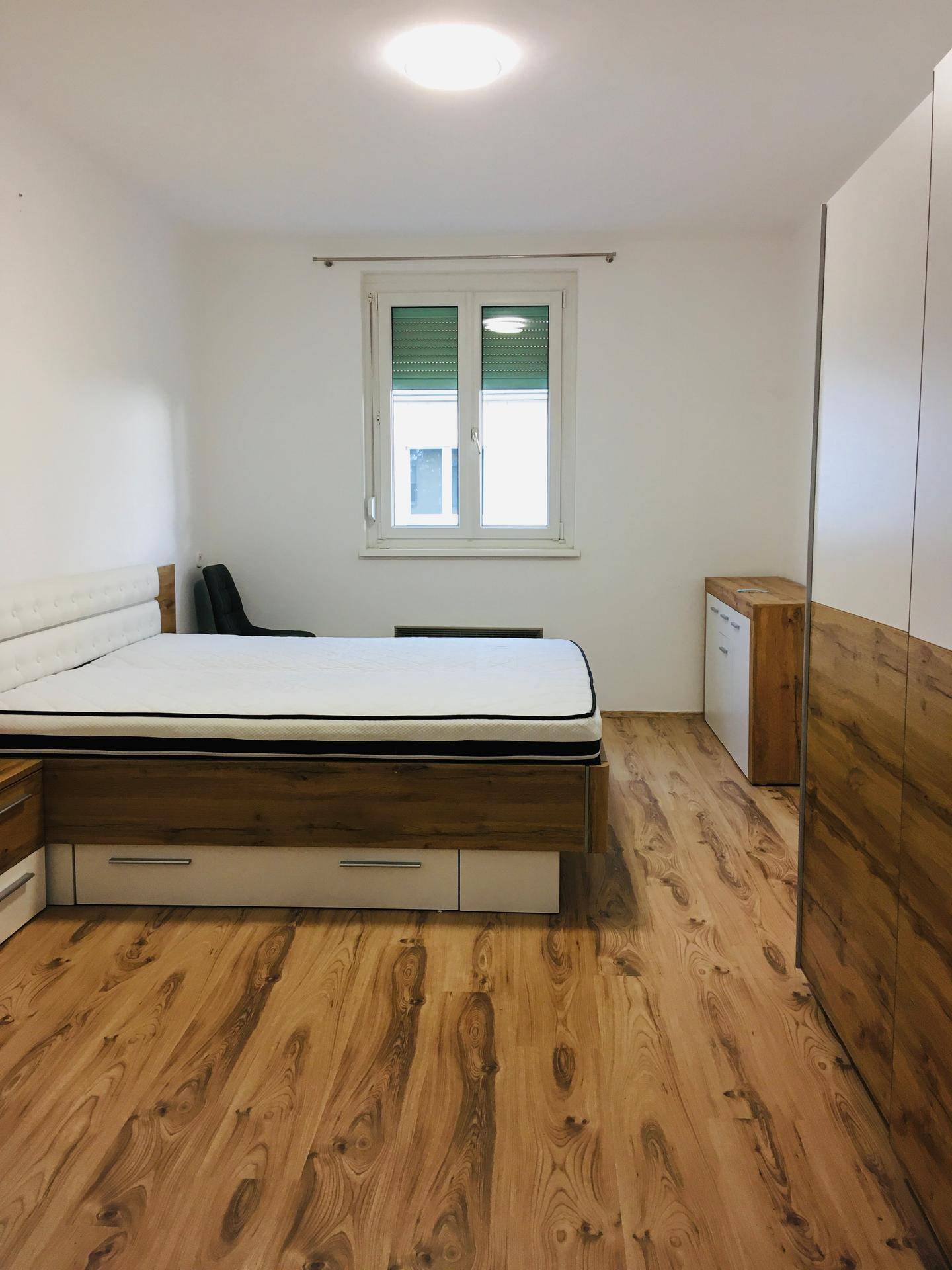 Gemütliches Schlafzimmer mit Doppelbett, großem Kleiderschrank und Laminatboden.