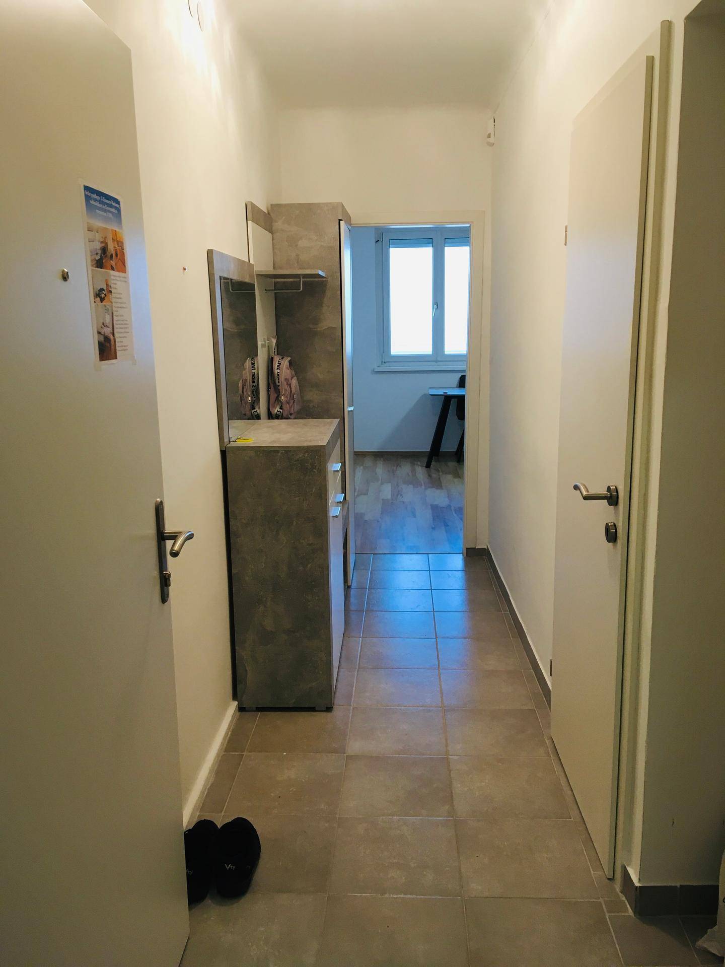 Heller Flur mit Fliesenboden und einem Durchgang zu weiteren Räumen der Wohnung.